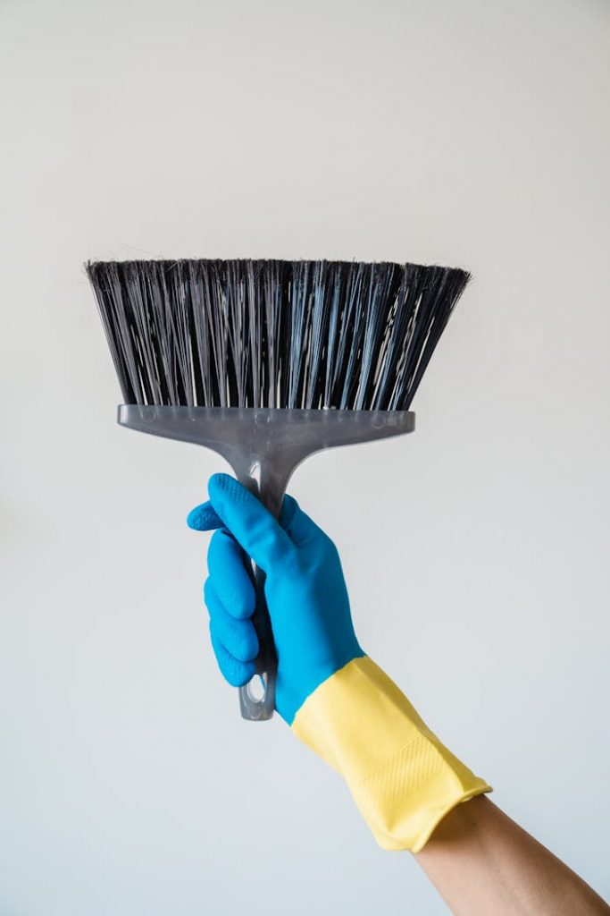 Close-up of a hand in a blue glove holding a broom, ideal for cleaning themes.